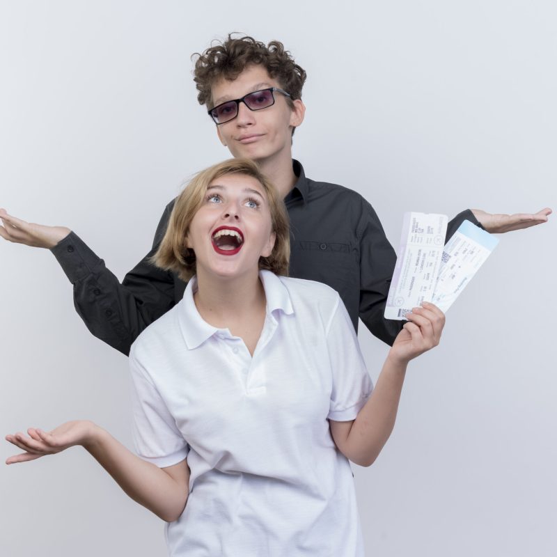 happy young couple of tourists man and woman with air tickets having fun together standing over white background