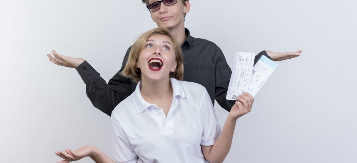 happy young couple of tourists man and woman with air tickets having fun together standing over white background happy young couple of tourists man and woman with air tickets having fun together standing over white background