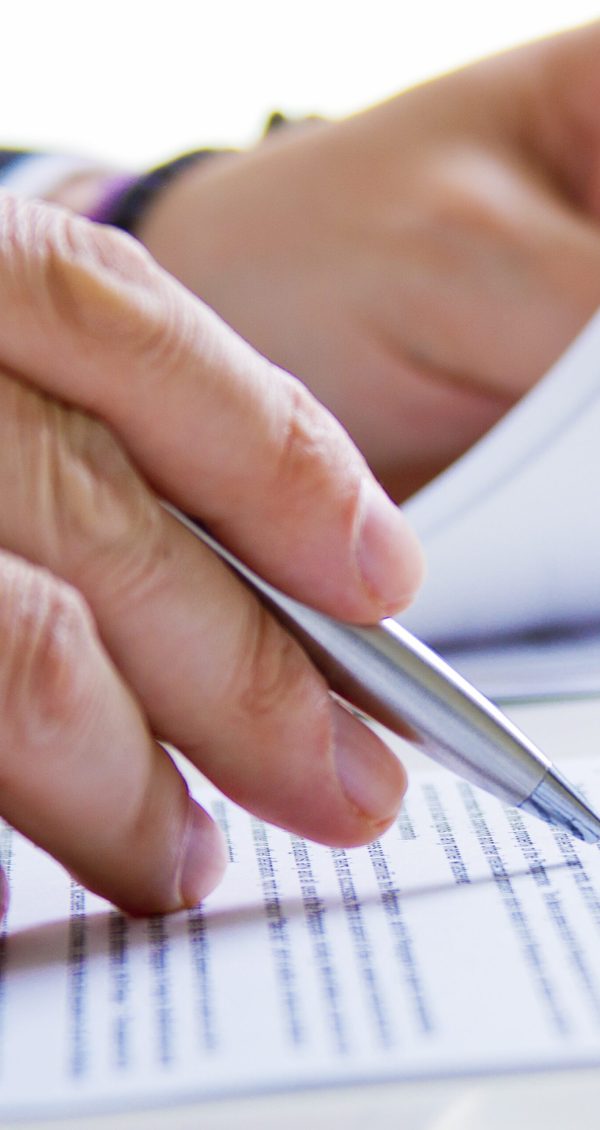 Hands of Business man in dark suit writing in his datebook